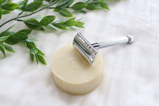 reusable metal safety razor sitting on a natural shaving soap