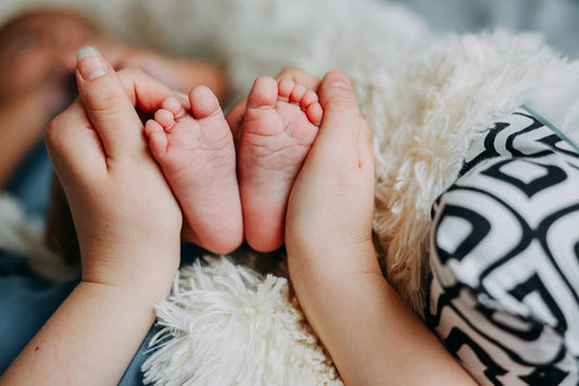 Baby's feet being held by mother on a cosy blanket